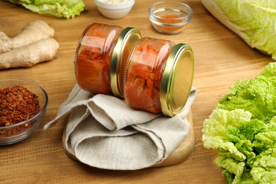 Delicious kimchi with Chinese cabbage and ingredients on wooden table, closeup