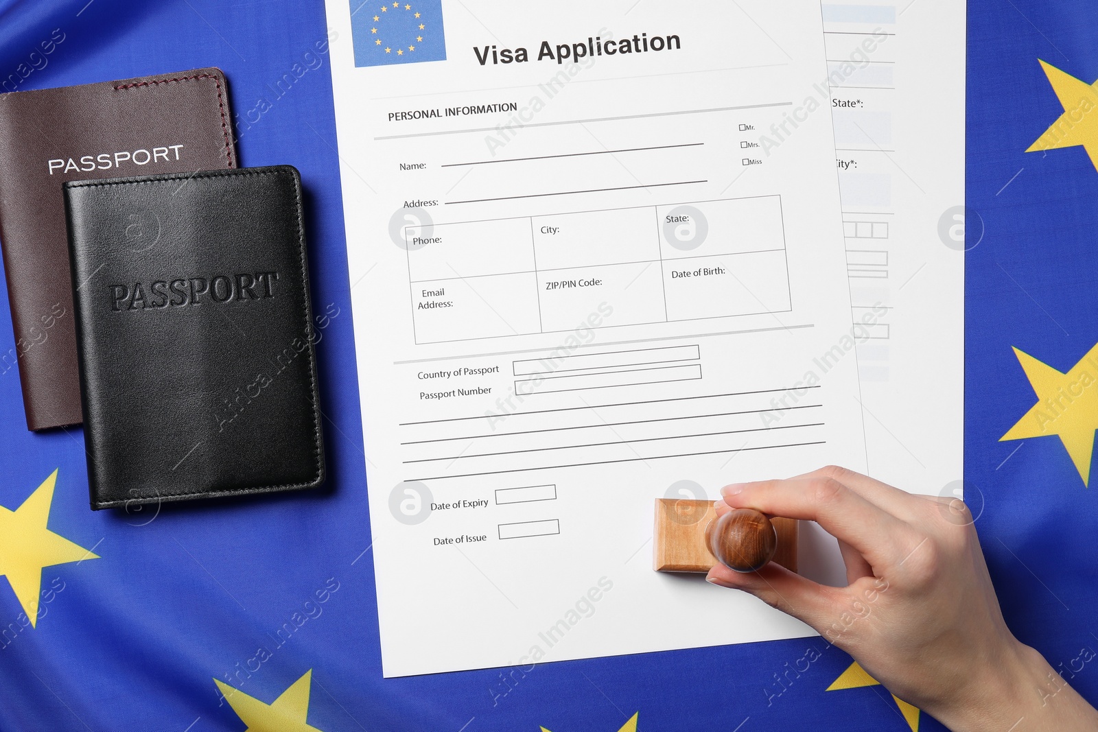 Photo of Immigration to European Union. Woman stamping visa application forms on flag, top view