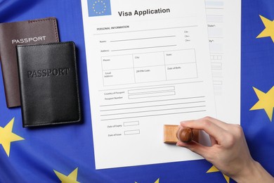 Immigration to European Union. Woman stamping visa application forms on flag, top view