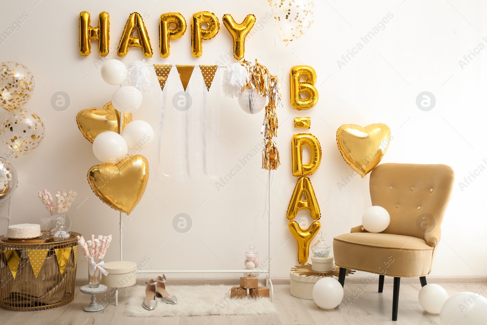 Photo of Phrase HAPPY BIRTHDAY made of golden balloon letters in decorated room