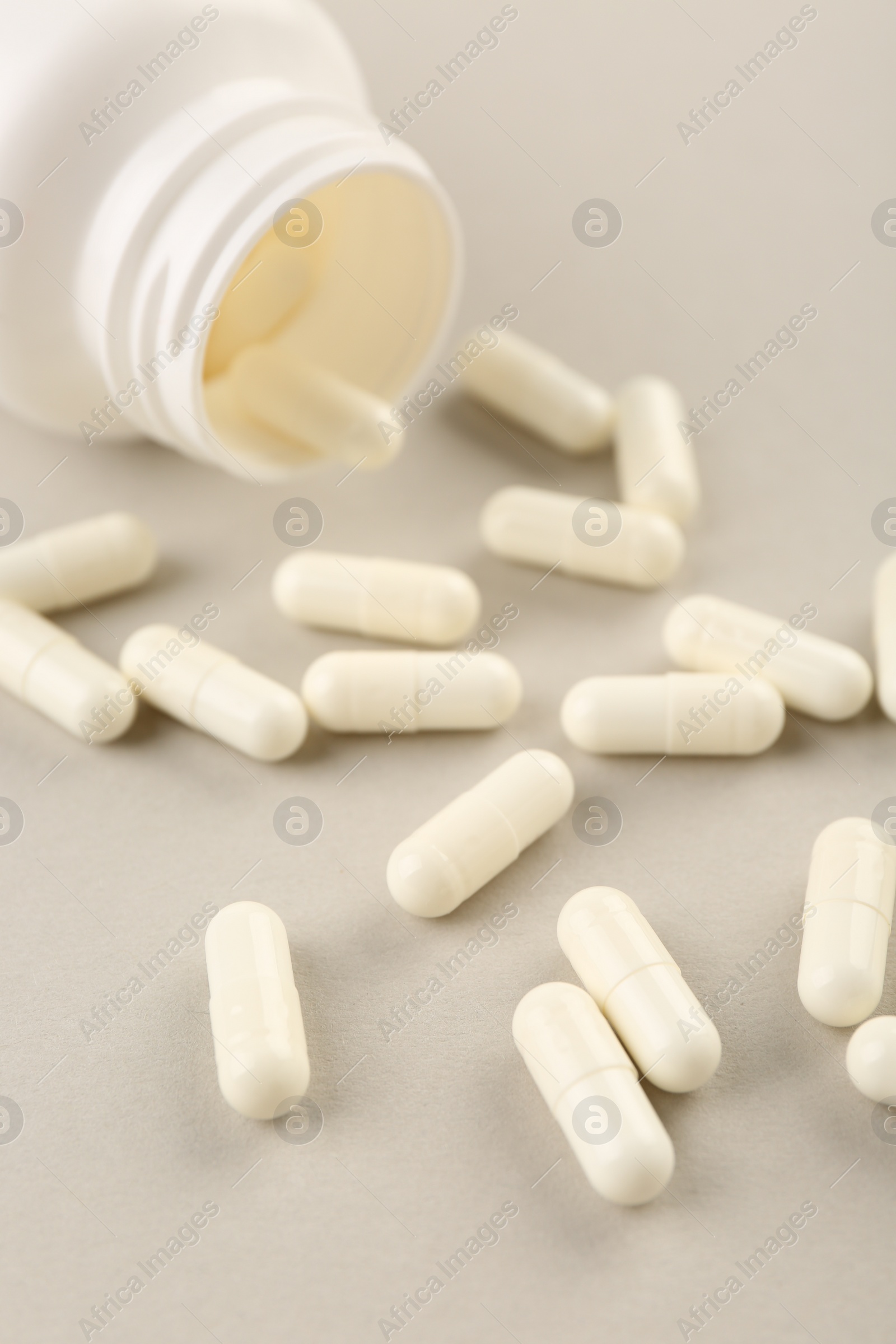 Photo of Bottle and vitamin capsules on light background, closeup