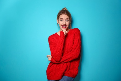 Beautiful young woman in warm sweater on color background