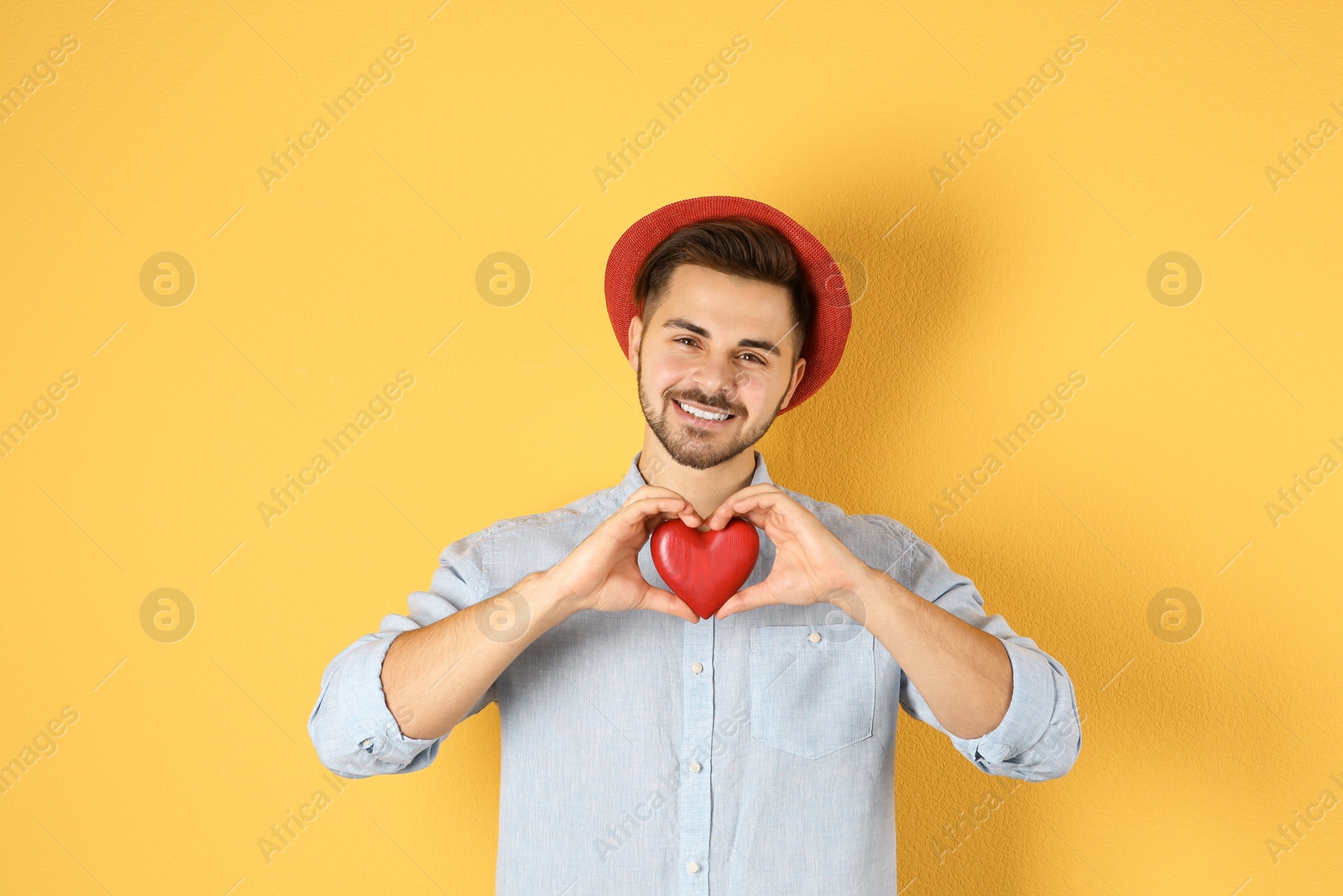 Photo of Man holding decorative heart on color background