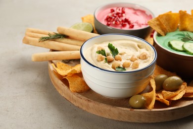 Photo of Different kinds of tasty hummus served with snacks on light table