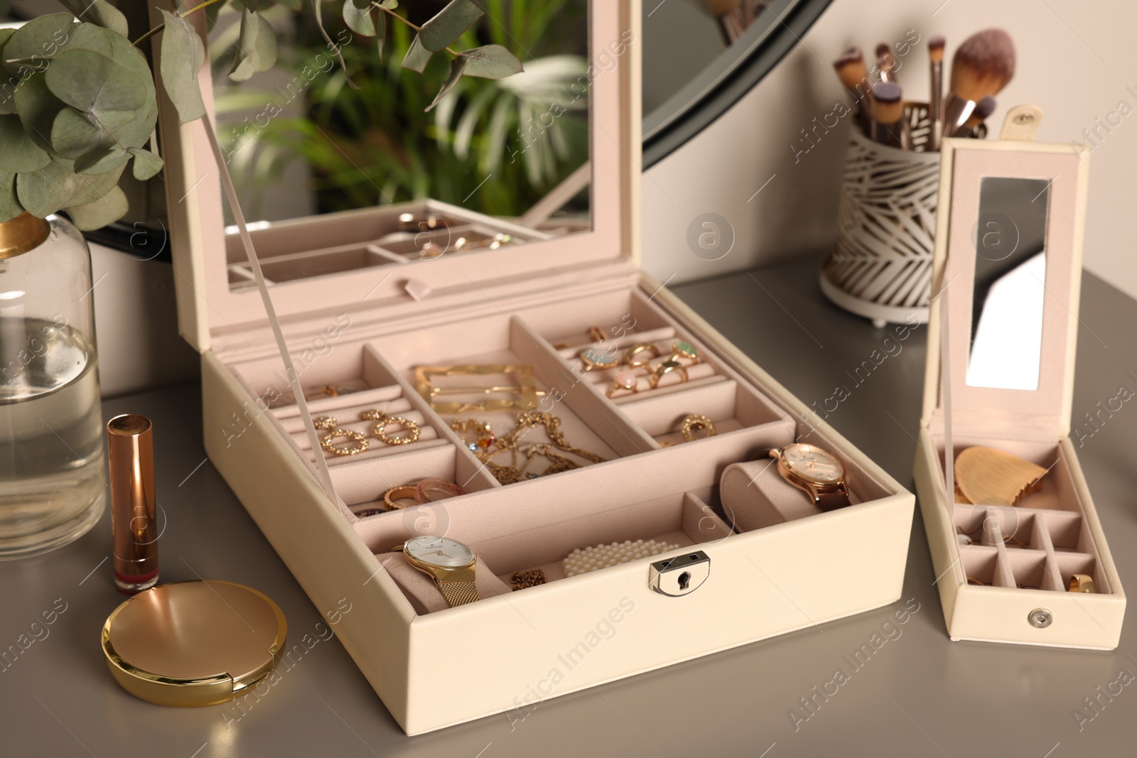 Photo of Elegant jewelry boxes with expensive wristwatches and beautiful bijouterie on grey table