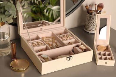 Elegant jewelry boxes with expensive wristwatches and beautiful bijouterie on grey table