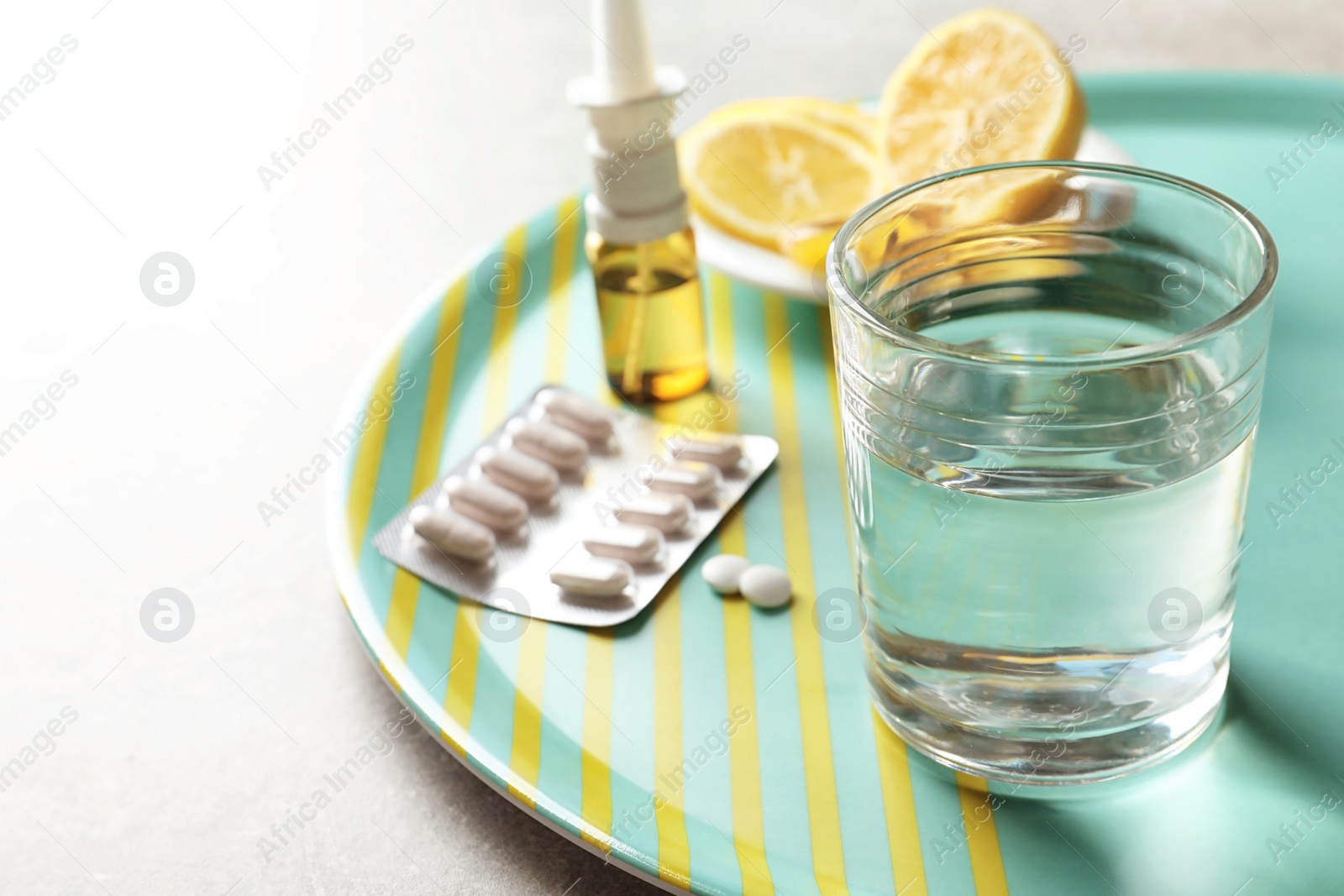 Photo of Glass with water and different cold remedies on tray