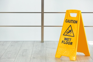 Safety sign with phrase Caution wet floor, indoors. Cleaning service