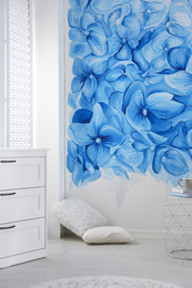 Photo of Stylish living room with blue flowers painted on wall. Floral pattern in interior design