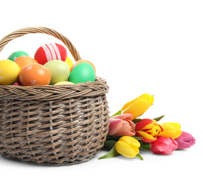 Photo of Bright Easter eggs in wicker basket and tulips isolated on white background