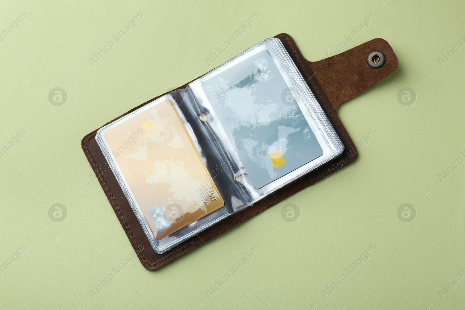 Photo of Leather card holder with credit cards on light green background, top view