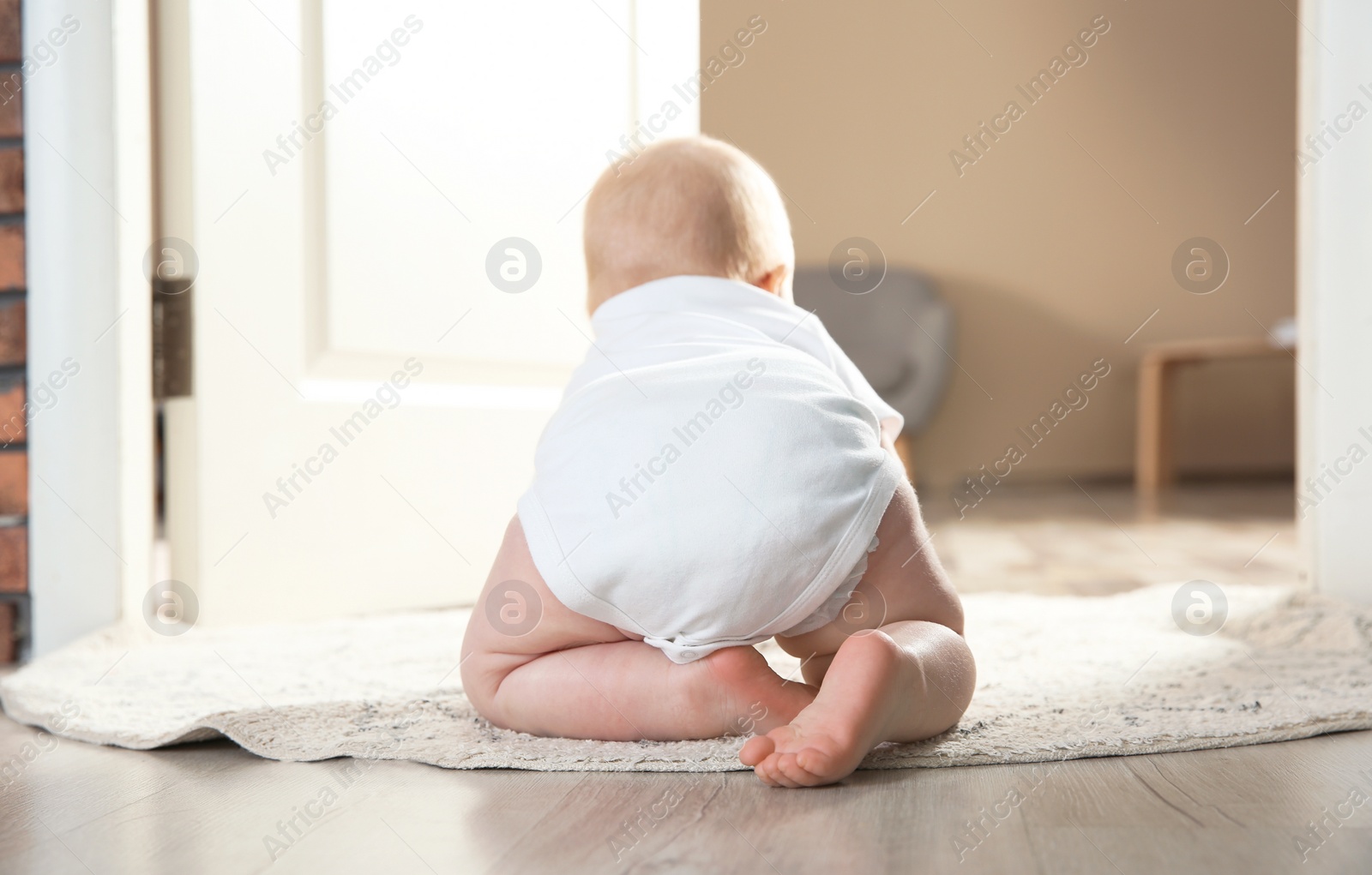 Photo of Cute little baby crawling on rug indoors