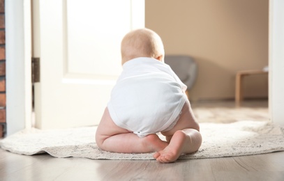 Cute little baby crawling on rug indoors