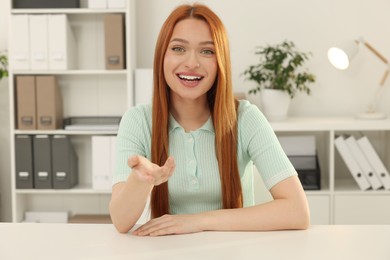 Young woman having video chat at table in office, view from web camera