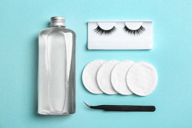 Flat lay composition with false eyelashes, lotion and tweezers on color background