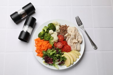 Balanced diet and healthy foods. Plate with different delicious products served on white tiled table, top view