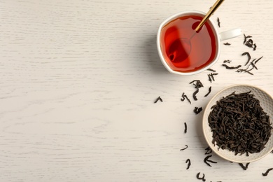 Photo of Cup of delicious tea with dried leaves on wooden background, top view