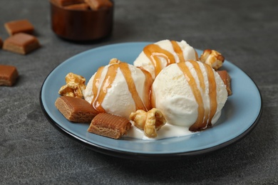 Photo of Delicious ice cream with caramel topping on grey table