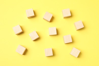 Photo of Many empty wooden cubes on yellow background, flat lay