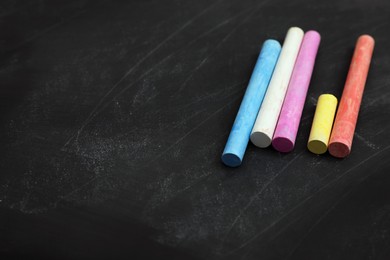 Photo of Colorful chalks on black board, space for text