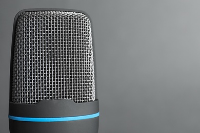 Professional condenser microphone on grey background, closeup with space for text. Musical equipment