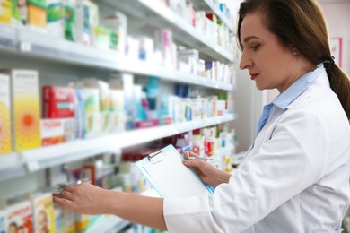 Photo of Professional pharmacist near shelves with merchandise in modern drugstore
