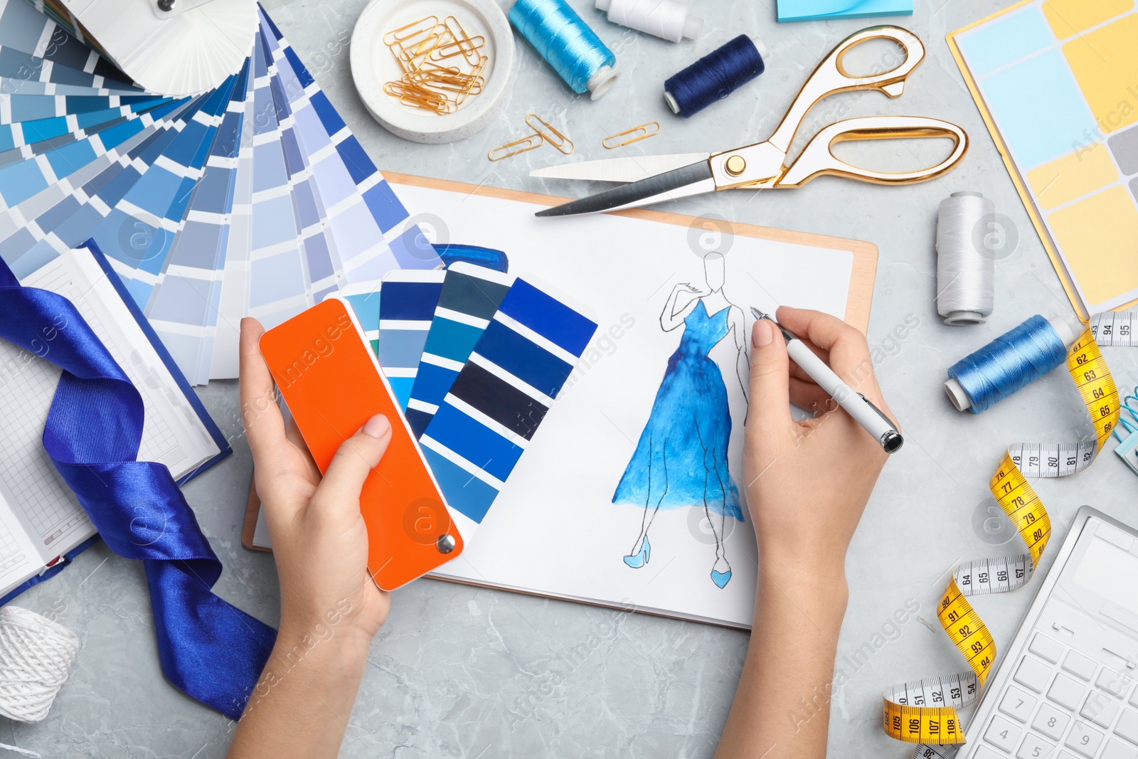 Photo of Fashion designer with color palette drawing dress at marble table, top view