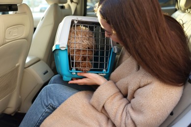 Photo of Woman with pet carrier travelling with her dog by car