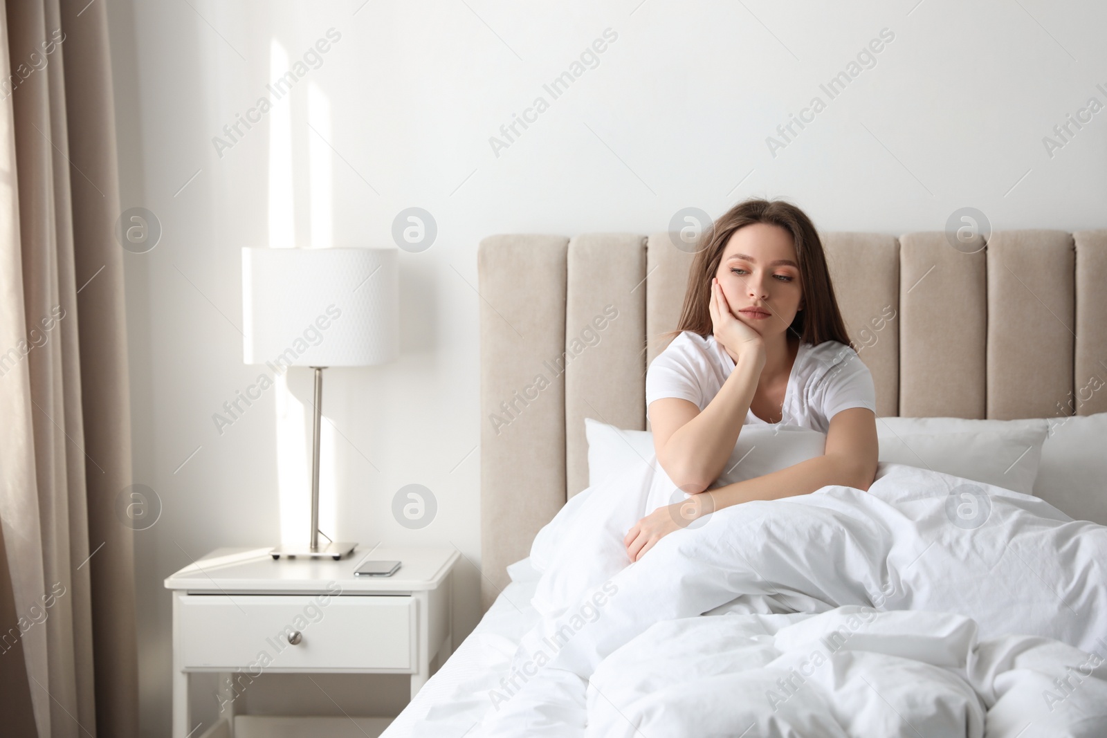 Photo of Unhappy young woman in bed at home. Relationship problems