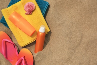 Flat lay composition with sunscreens on sand, space for text. Sun protection care