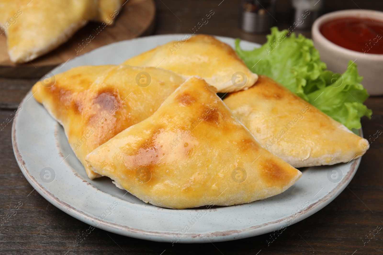 Photo of Delicious samosas and lettuce on wooden table, closeup
