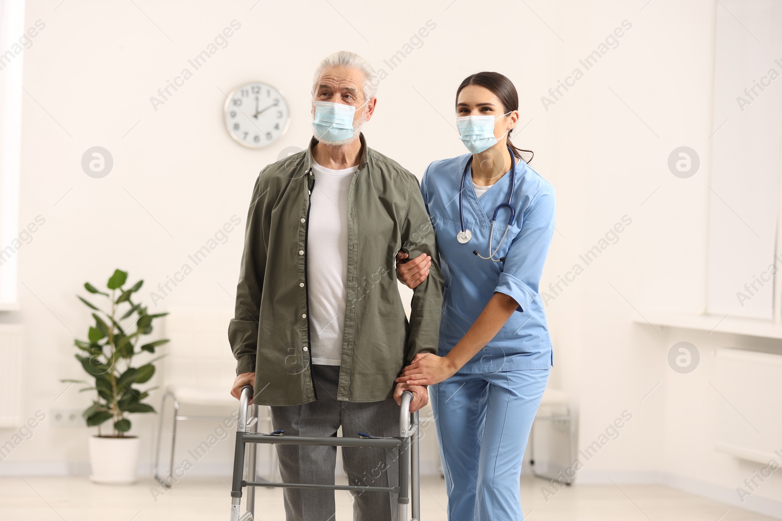 Photo of Young nurse supporting elderly patient in hospital