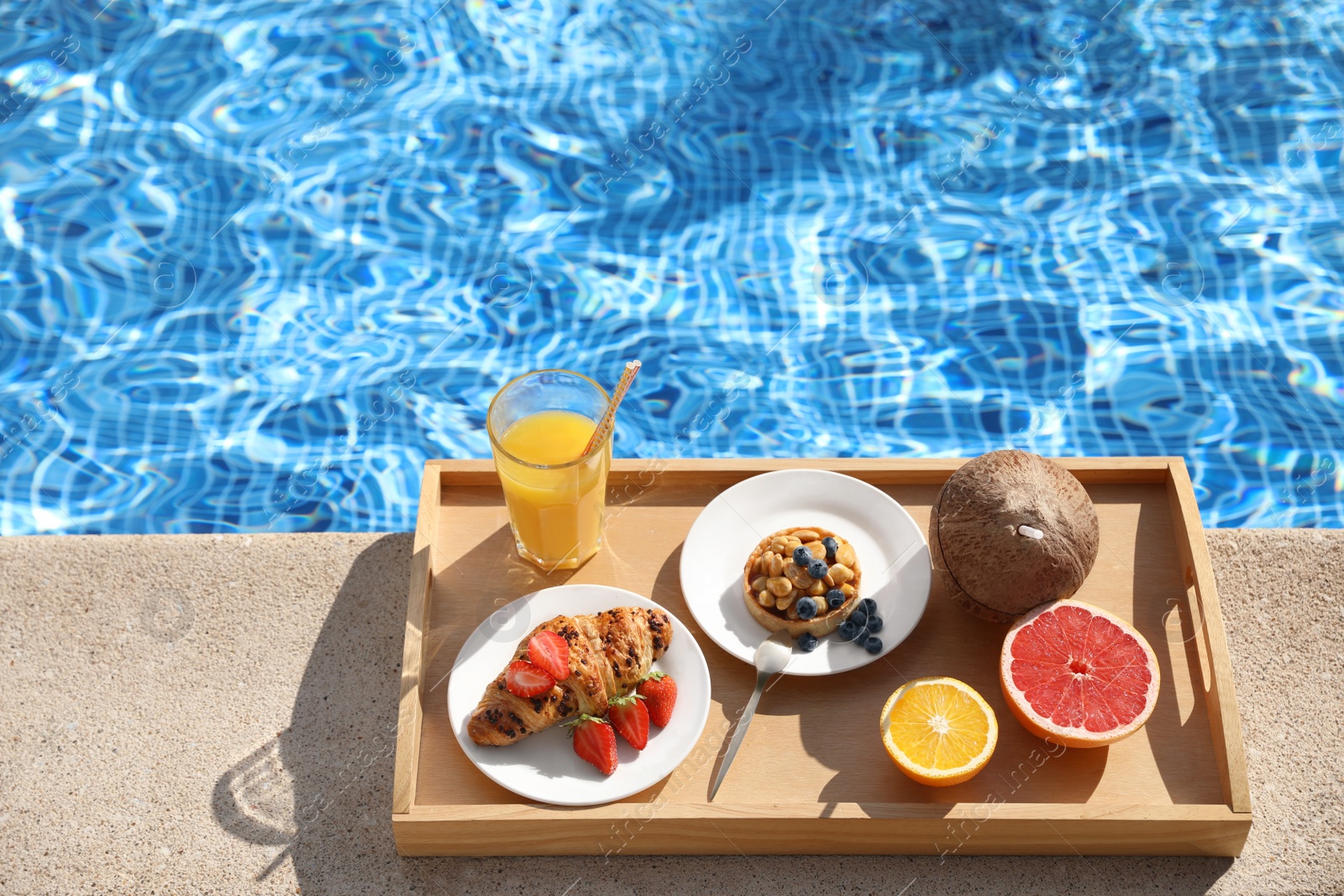 Photo of Tray with delicious breakfast near swimming pool