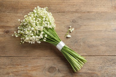 Beautiful lily of the valley bouquet on wooden table, top view