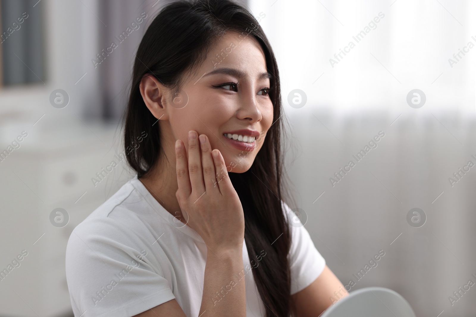 Photo of Woman with perfect skin looking at mirror indoors