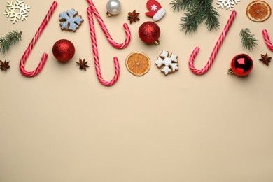 Photo of Flat lay composition with sweet candy canes and Christmas decor on beige background, space for text