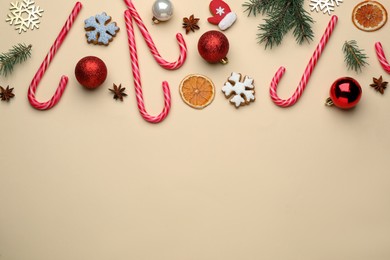 Flat lay composition with sweet candy canes and Christmas decor on beige background, space for text