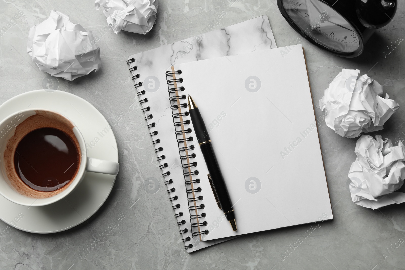 Photo of Flat lay composition notebooks and crumpled paper balls on grey marble table. Space for text