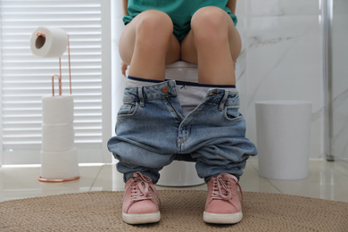 Photo of Woman suffering from hemorrhoid on toilet bowl in rest room, closeup