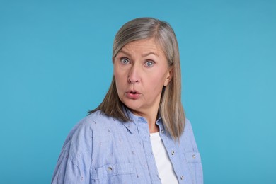 Portrait of surprised senior woman on light blue background