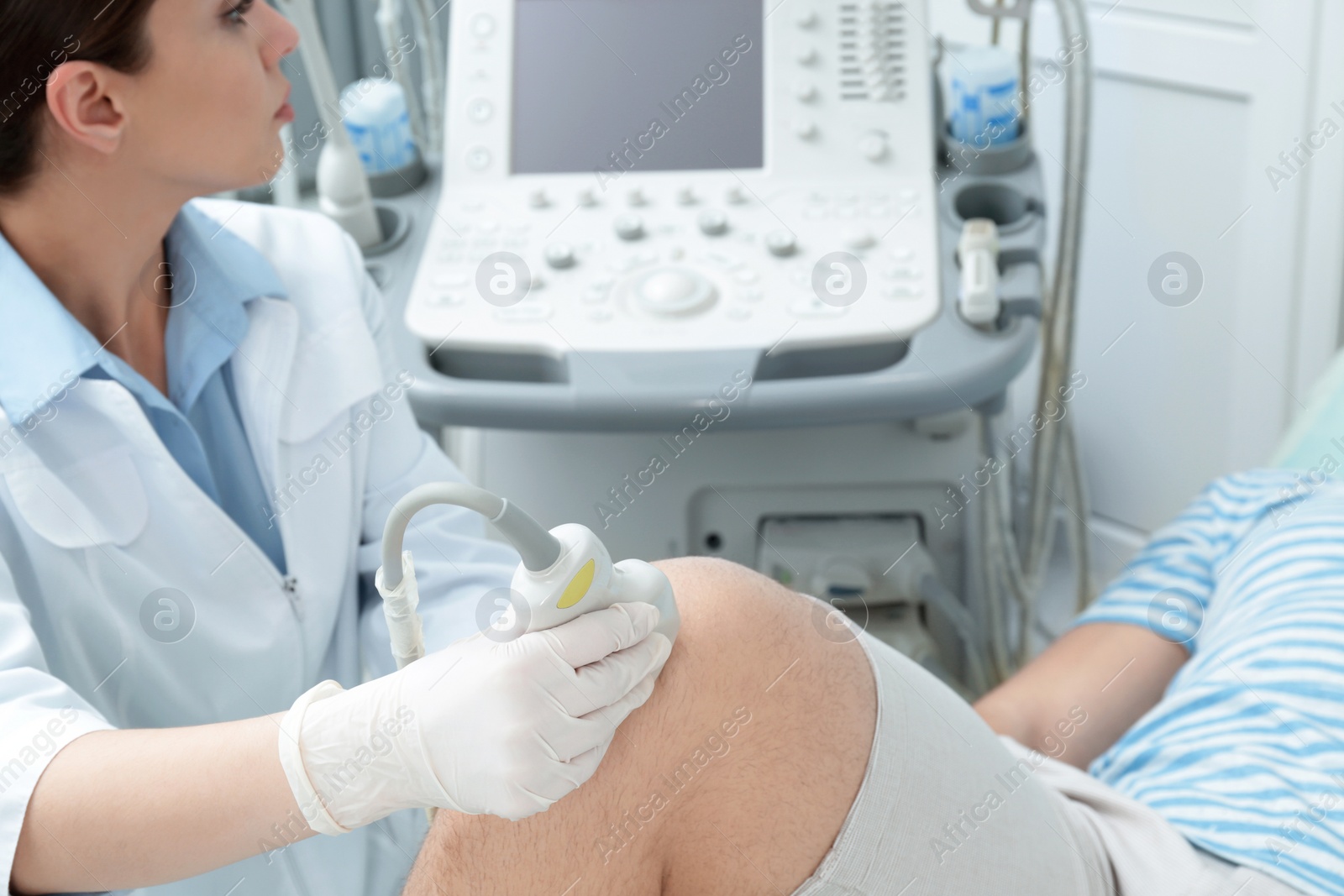 Photo of Doctor conducting ultrasound examination of patient's knee in clinic