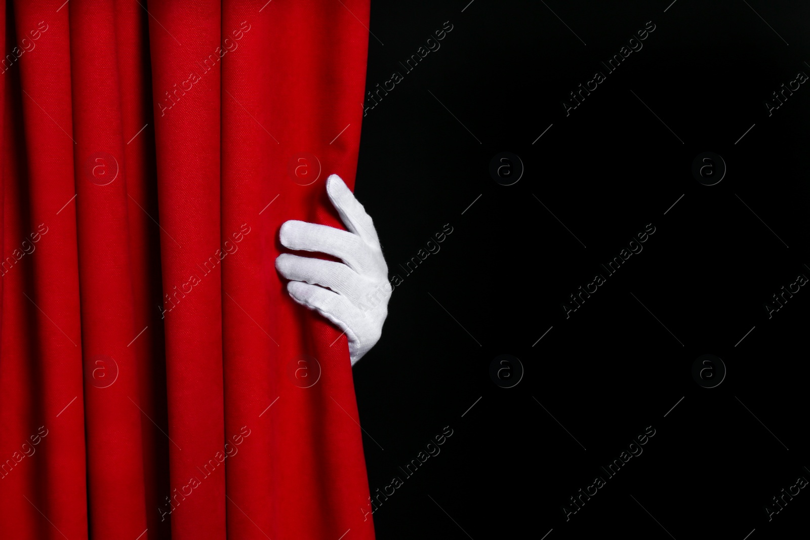 Photo of Person opening red front curtains on black background, closeup. Space for text