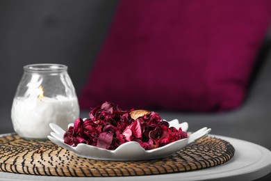 Aromatic potpourri of dried flowers and burning candle on table indoors