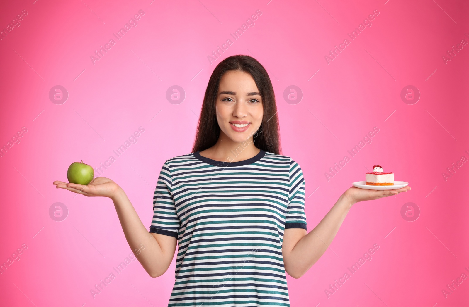 Photo of Concept of choice. Woman holding apple and cake on pink background