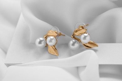 Photo of Beautiful earrings on white fabric. Luxury jewelry