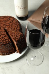 Photo of Delicious chocolate truffle cake and red wine on grey table