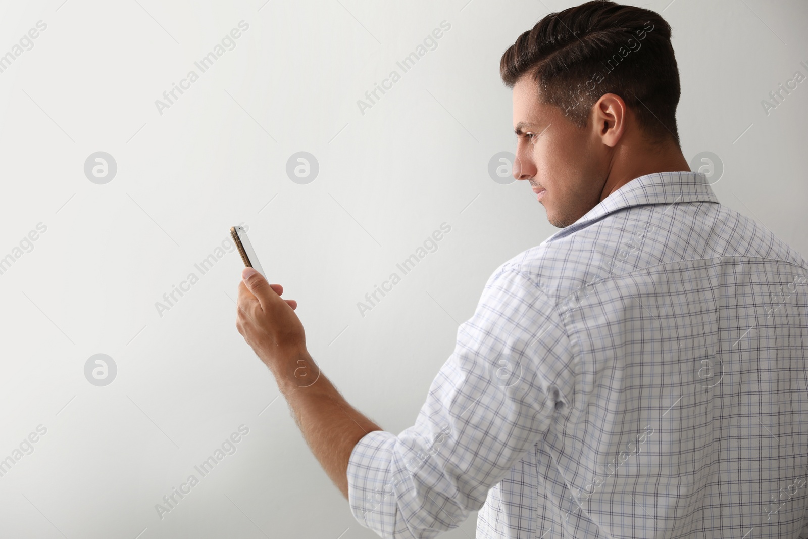 Photo of Man unlocking smartphone with facial scanner on white background. Biometric verification