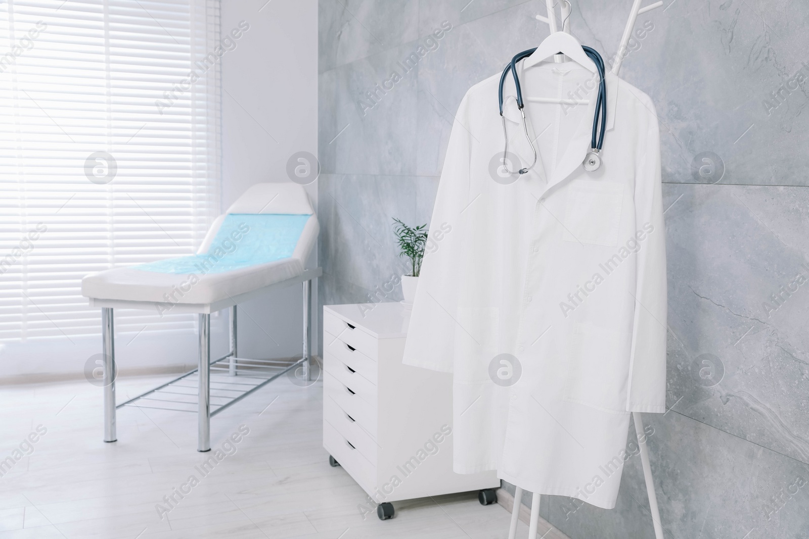 Photo of White doctor's gown and stethoscope on rack in clinic