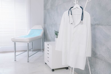 Photo of White doctor's gown and stethoscope on rack in clinic