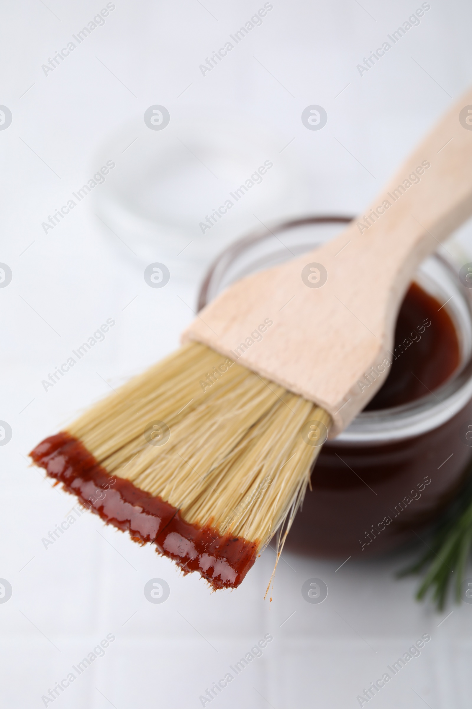 Photo of Marinade in jar and basting brush on white table, closeup